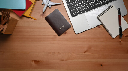Laptop computer, notebook, passport and airplane on wooden table.Preparation for Traveling concept.