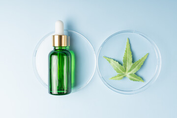 Cannabis face beauty serum or oil dropper concept. Natural cosmetic. CBD oil, THC tincture and hemp leaves on a blue background.