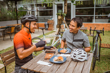 two cyclist enjoying coffee in the cafe after riding - obrazy, fototapety, plakaty