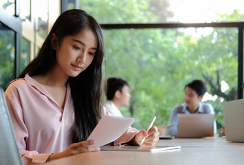 Attractive asian businesswoman using stylus pen writing on digital tablet while sitting in meeting...