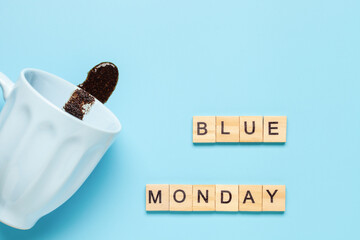 Board with Blue monday text and cup with spilled coffee on blue background. Blue monday concept. Top view