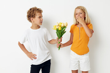 two joyful children with a bouquet of flowers gift birthday holiday childhood light background