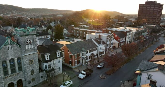 Beautiful aerial of USA town in winter. Warm sunshine above homes, church, business buildings.