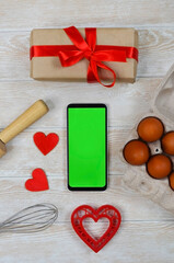 Fototapeta na wymiar red festive ingrediens for cooking, valentines day eggs, rolling pin and whisk, cutter dish shape heart for baking cake flat lay, chroma key smart phone copy space