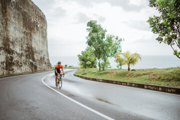 asian male cyclist riding in beautiful road
