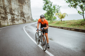 male cyclist pushing his bike and walk after struggling to climb - obrazy, fototapety, plakaty