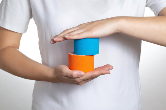 A girl holds in her hands a blue and orange tape for taping on the background of a white t-shirt, close-up