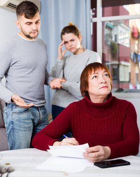 Dissatisfied man with his wife pointing to some paper to offended elderly mother