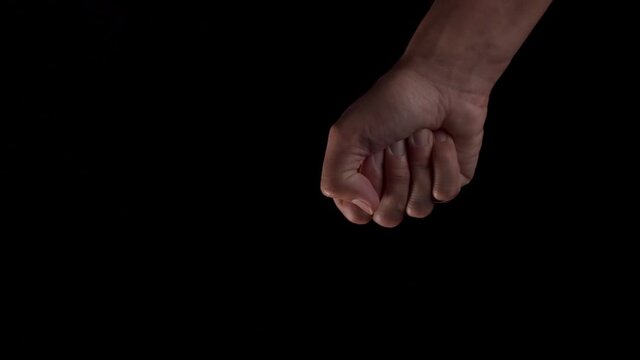A human hand opening and closing, making a fist with a dark background.