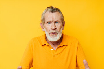 Obraz premium Portrait of happy senior man yellow shirt posing emotions yellow background