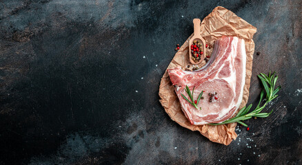 Organic Pork meat chop set with spices and rosemary and red pepper on black table. Long banner format. top view