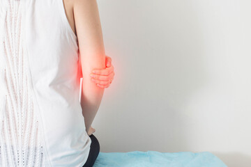 The girl holds on to the sore elbow on which there is pain and redness. Elbow disease concept,...