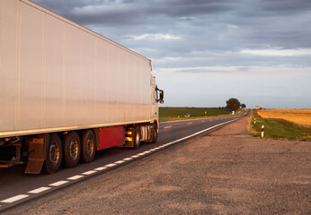 A truck with a white semi-trailer refrigerator transports perishable cargo in the summer against...