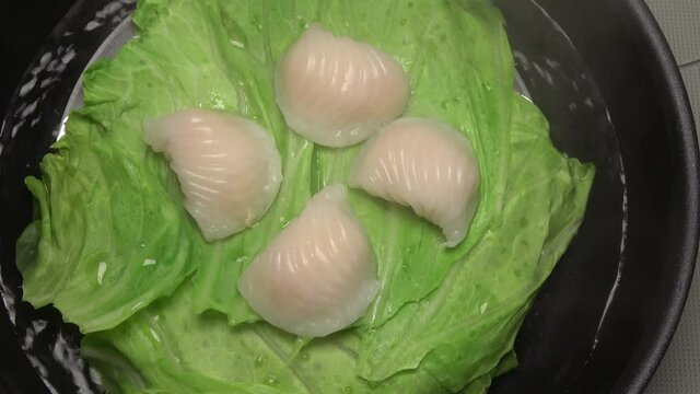 Closeup shot of steaming dim sum shrimp dumplings in the steamer. Cooking Har Gow, Chinese crystal prawn dumpling. 4K