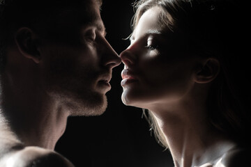Romantic night date. Romantic couple in love looking at each other, embracing and kissing on black background.