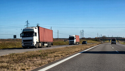 A convoy of two trucks with container trailers transports heavy containers from the seaport. The...