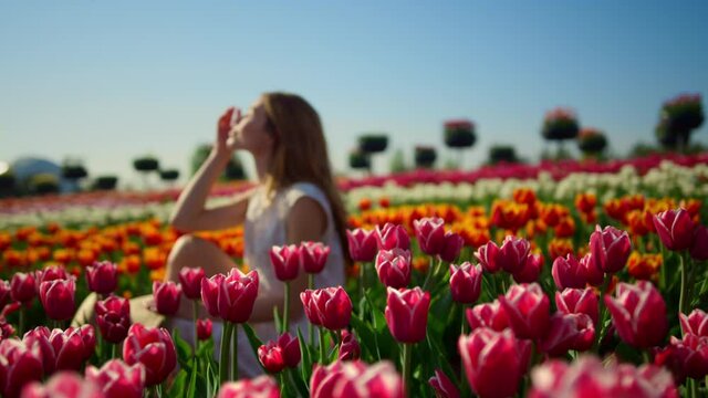 Young woman smiling in bright flower garden. Woman profile in flower background.