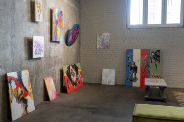 Collection of creative paintings of various artists on walls of empty room and table with flutes of champagne prepared for opening event