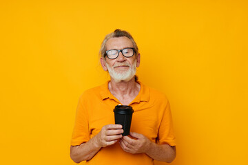 Photo of retired old man in a yellow T-shirt a glass with a drink isolated background