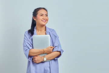 Portrait of cheerful young Asian woman holding a laptop and looking aside isolated on white background