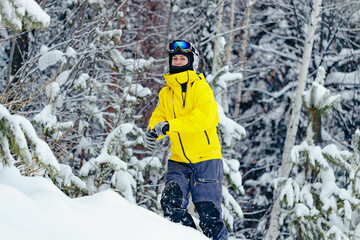 Fototapeta na wymiar Portrait of a young woman snowboarder in bright winter clothes. A female of Caucasian ethnicity spends time in a snowy snowboard park. Winter vacation outdoors.