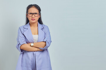 Portrait of surprised young asian woman standing with crossed arms, looking at camera isolated on...