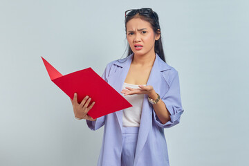 Obraz premium Portrait of surprised young Asian business woman in suit standing pointing at document folder with palms isolated on purple background