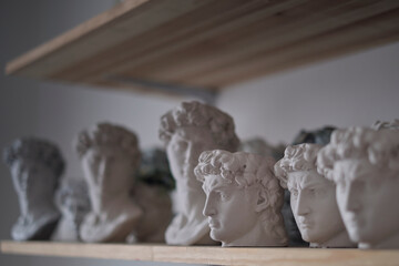 group of busts of David stand on a shelf. sculptor's workspace. antique plaster busts