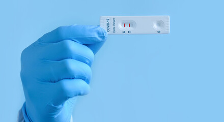 Obraz premium Doctor's hand in medical gloves shows a rapid laboratory test for COVID-19 Delta variant strain to detect IgM and IgG antibodies to the new coronavirus. The test shows a positive result.
