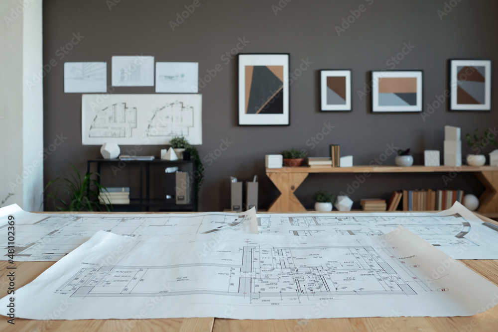Poster interior of contemporary office of engineers or architects with large unrolled blueprint with sketch