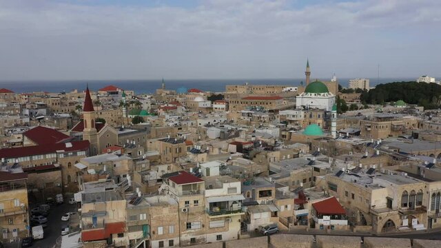 Slow drone flight over narrow residential neighborhoods towards iconic Al-Jazzar mosque and Terra Sancta church in Akko (Acre), religion and historic landscapes in Israel
