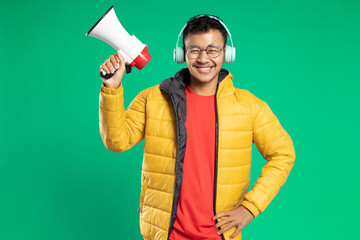 handsome asian young man smiling holding megaphone on green background