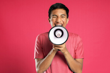 Handsome young man over isolated red background shouting through a megaphone