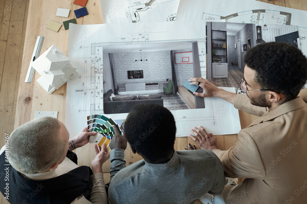 Aufkleber overview of contemporary designers bending over workplace with blueprint and photos of interior whil