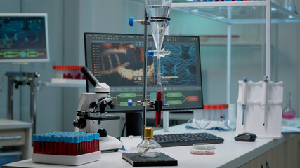 Chemical experiment with test tube in laboratory used for scientific innovation. Sample of blood in flask prepared for examination analysis on desk with vacutainers, pipette and microscope