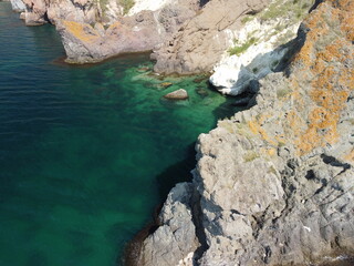 Aerial view from above on calm azure sea and volcanic rocky shores. Small waves on water surface in motion blur. Nature summer ocean sea beach background. Nobody. Holiday, vacation and travel concept
