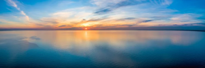 Poster Breed luchtpanorama van zeegezicht - zonsondergang die in kalme zee weerspiegelt © Greg Brave