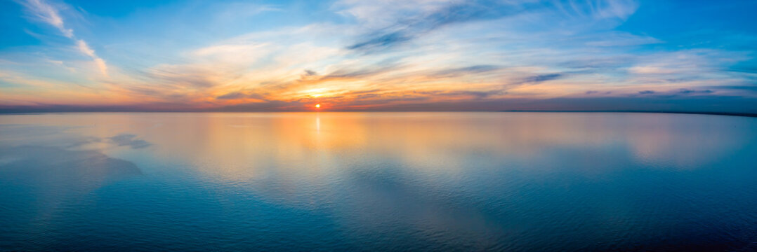 Wide aerial panorama of seascape - sunset reflecting in calm sea