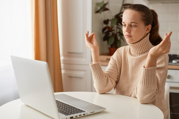 Portrait of relaxed woman with ponytail hairstyle wearing casual style beige sweater sitting at...