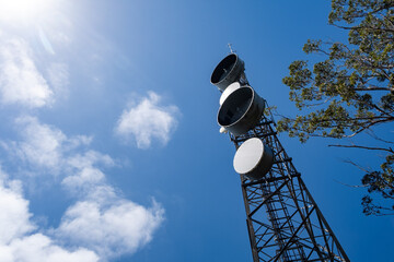 Looking up at telecommunications tower against blue sky with copy space - 481104767