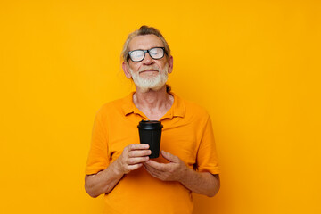 Portrait of happy senior man in a yellow T-shirt a glass with a drink cropped view