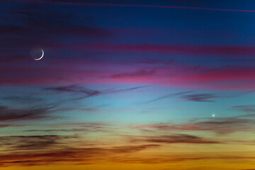 Crescent young Moon and planets on colorful sky.