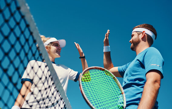 Talent wins games, teamworks wins championships. Low angle shot of two young tennis players giving each other a high five outdoors on the court.