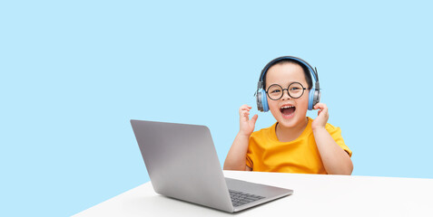 Little boy wearing headphones using laptop, happy learning,  listening audio course, e-learning education concept