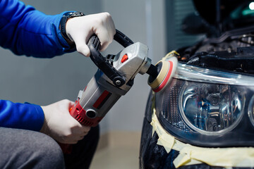 Car headlights cleaning with power buffer machine at car service