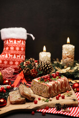 Traditional French terrine covered with bacon on dark wooden background with Christmas decorations