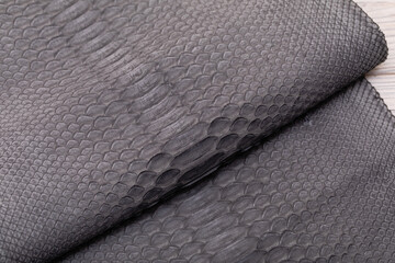 grey suede dyed genuine natural python leather on the wooden table	