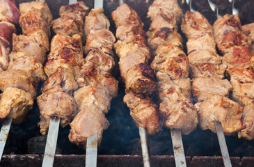 Pork meat is grilled on metal skewers.
