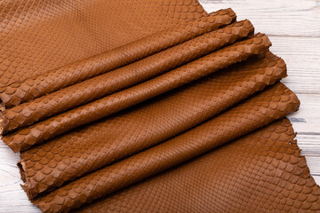 brown dyed folded natural genuine python leather on the wooden table
