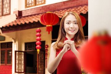 Asian Chinese woman in a cheongsam dress with congratulations gesture